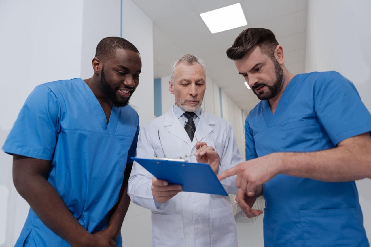 Clinician and trainees reviewing pathway documentation in a clinical setting.